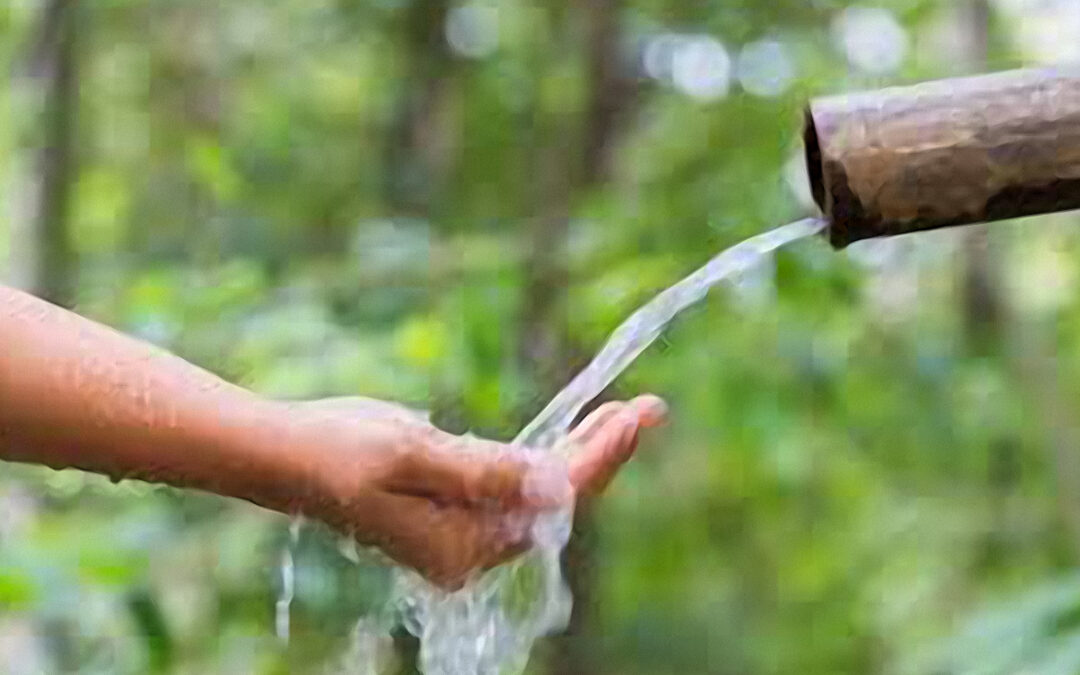 Water flows generously from a pipe into someone's hand, symbolizing the act of giving and the abundance that comes from sharing resources.